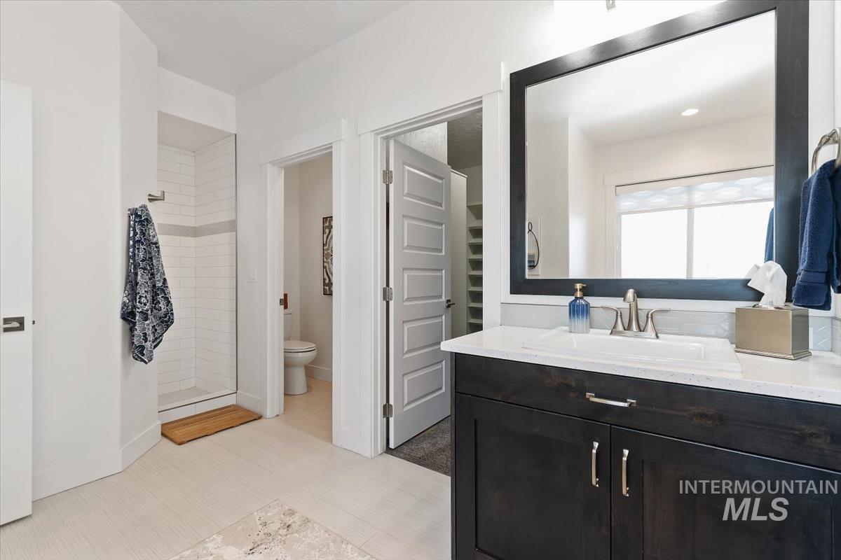 Bathroom with vanity, a walk in closet, and tiled shower