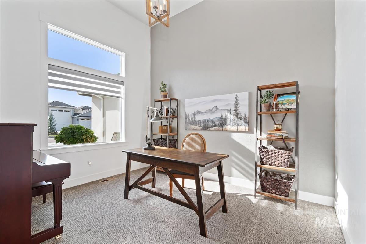 Office space featuring light carpet, a chandelier, and a high ceiling