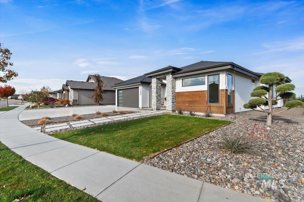 Prairie-style house featuring stone siding, an attached garage, a front lawn, concrete driveway, and stucco siding