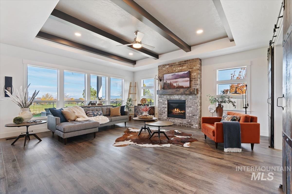 Living area featuring a raised ceiling, beam ceiling, dark wood-style floors, and healthy amount of natural light