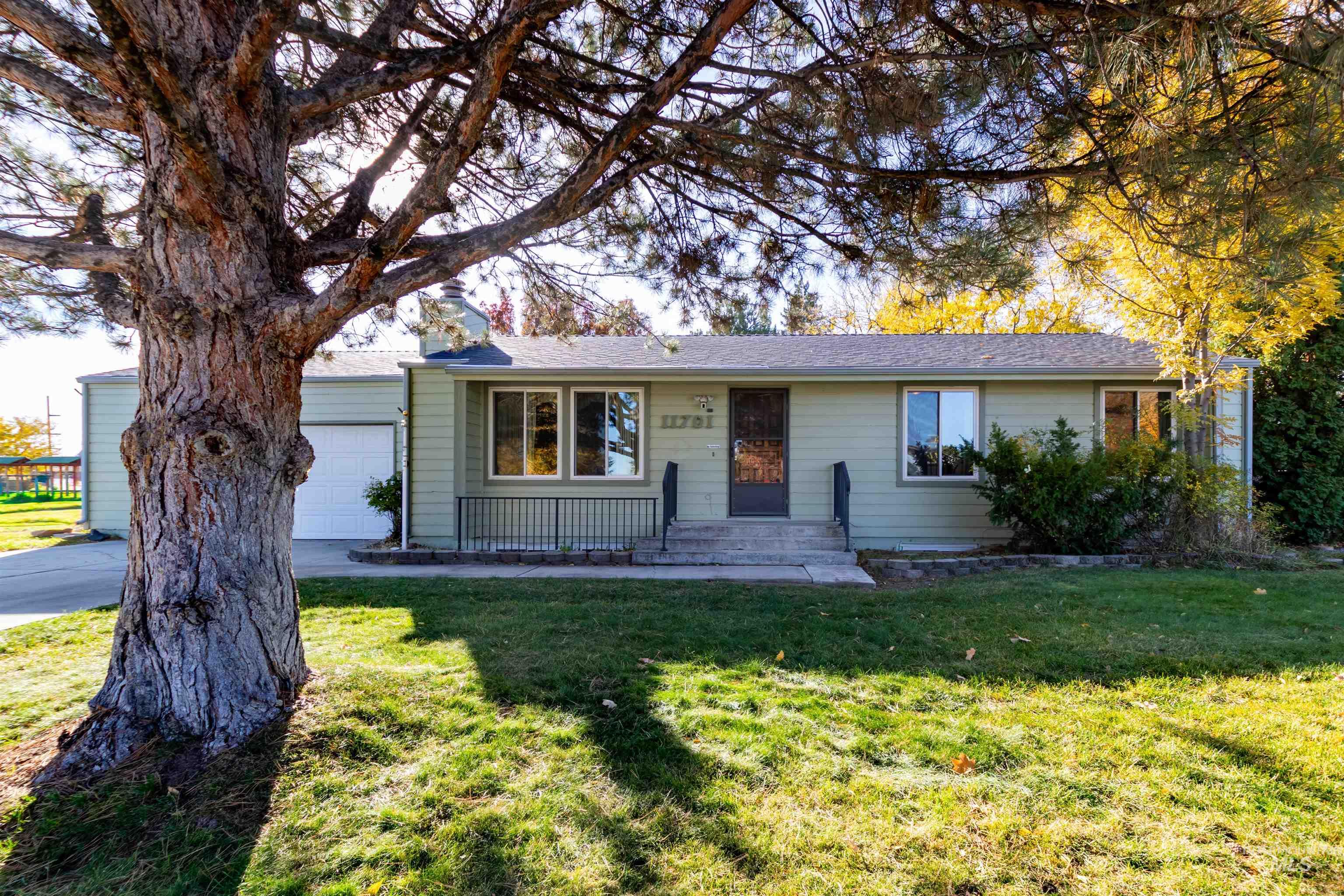 Ranch-style house featuring a front yard, a garage, and a chimney