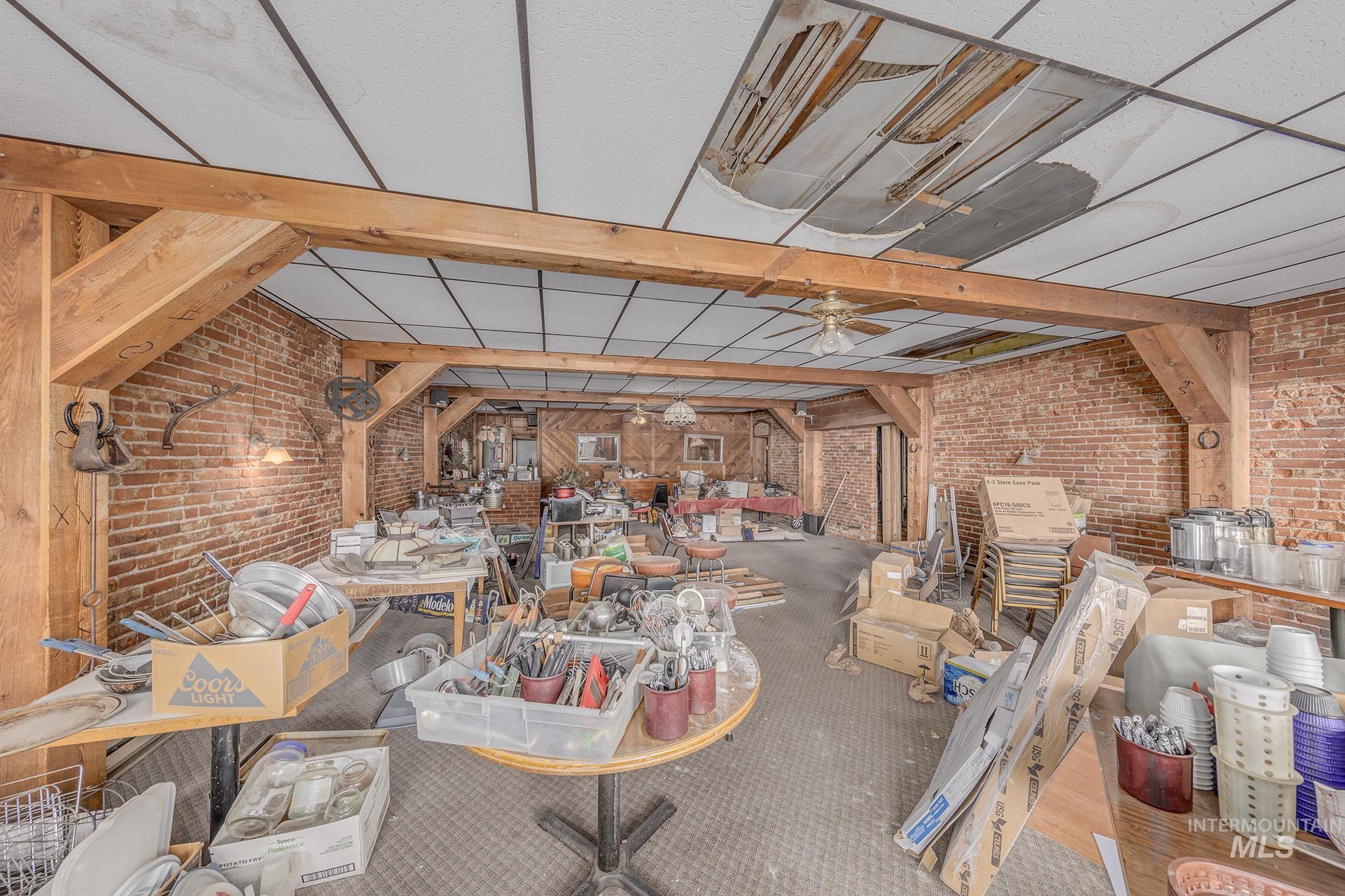 Miscellaneous room featuring brick wall, a ceiling fan, and a paneled ceiling