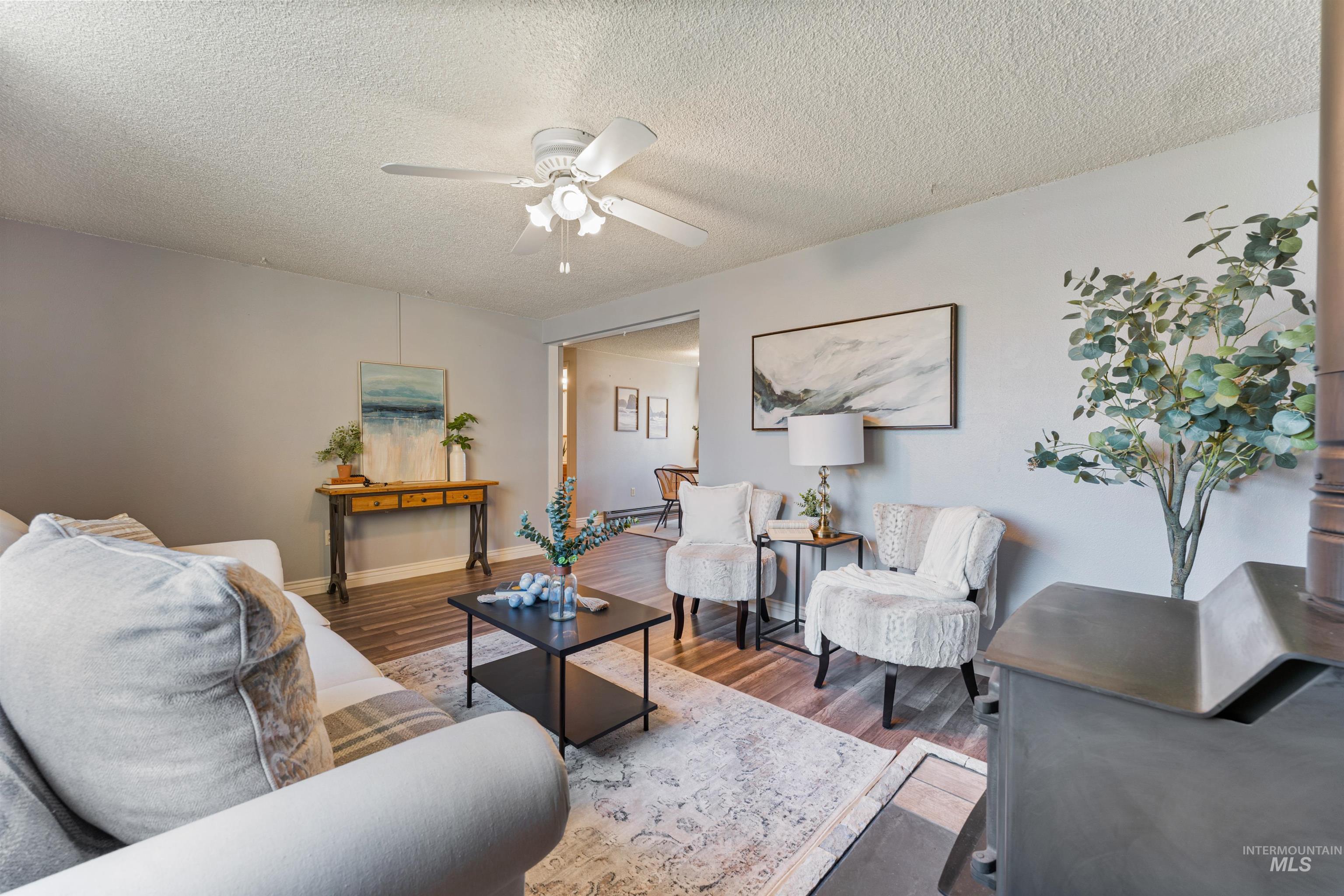 Living area featuring wood finished floors, a textured ceiling, and a ceiling fan