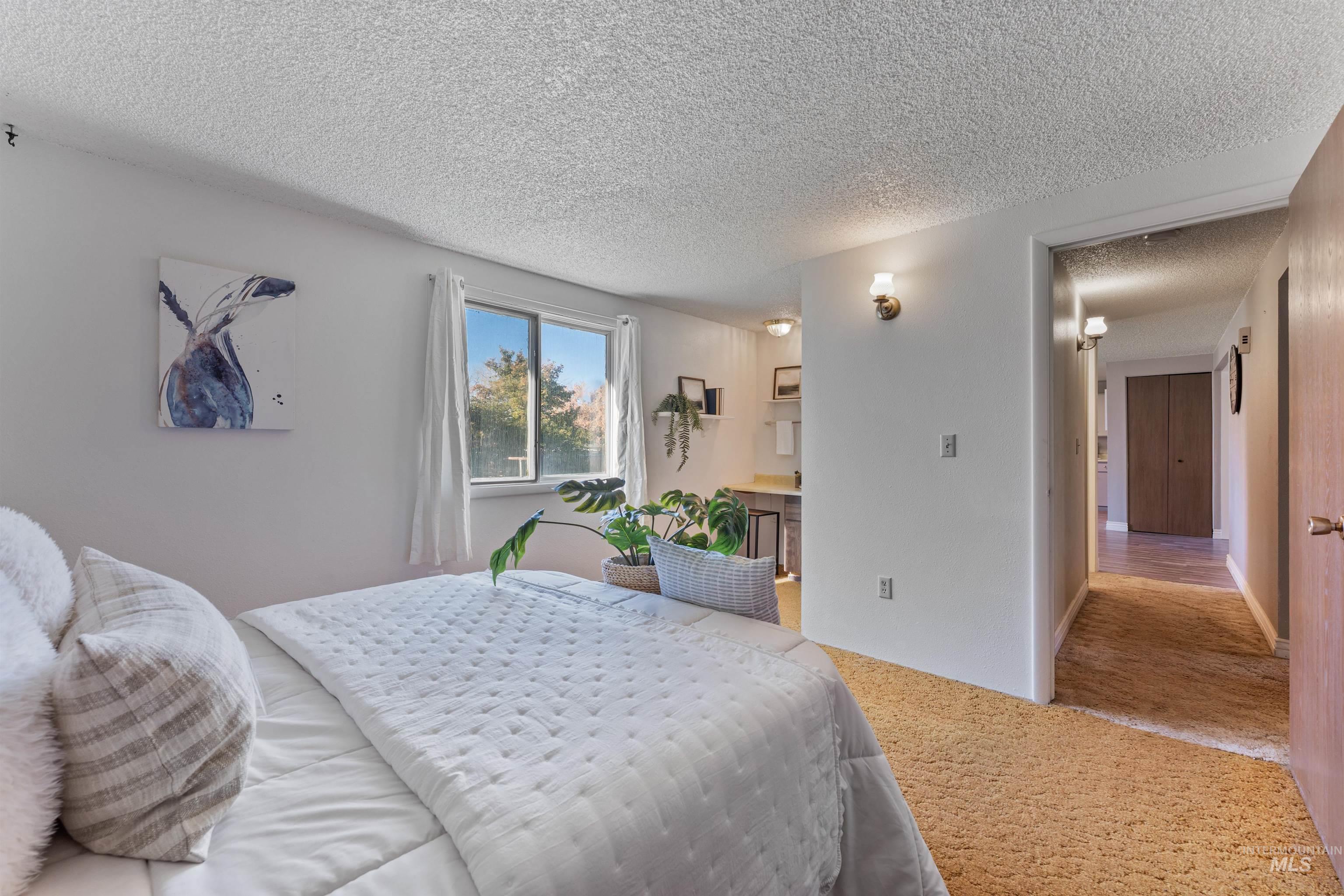 Bedroom with carpet, connected bathroom, and a textured ceiling