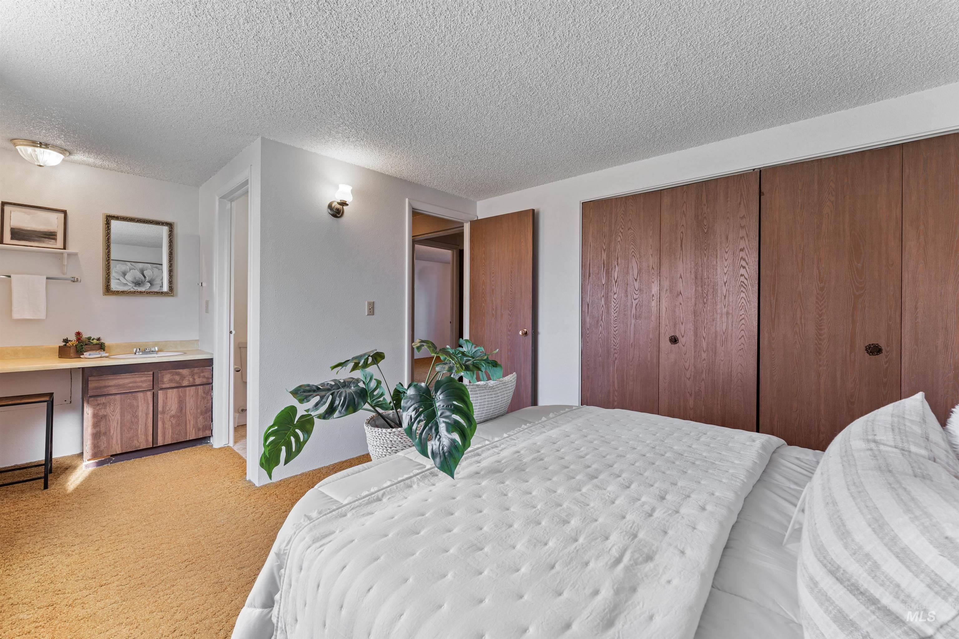 Bedroom with light colored carpet, a closet, and a textured ceiling
