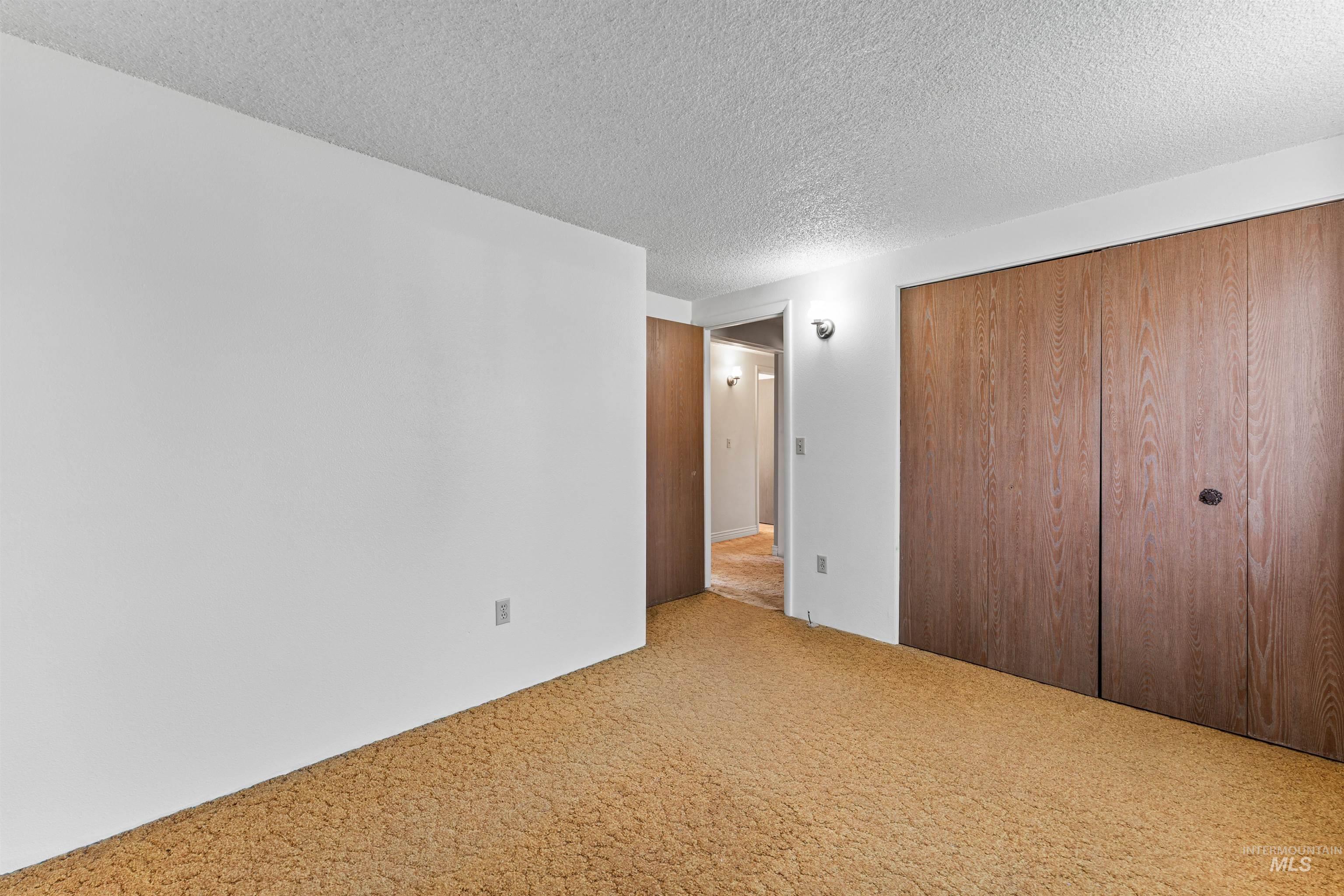 Unfurnished bedroom featuring carpet flooring, a closet, and a textured ceiling