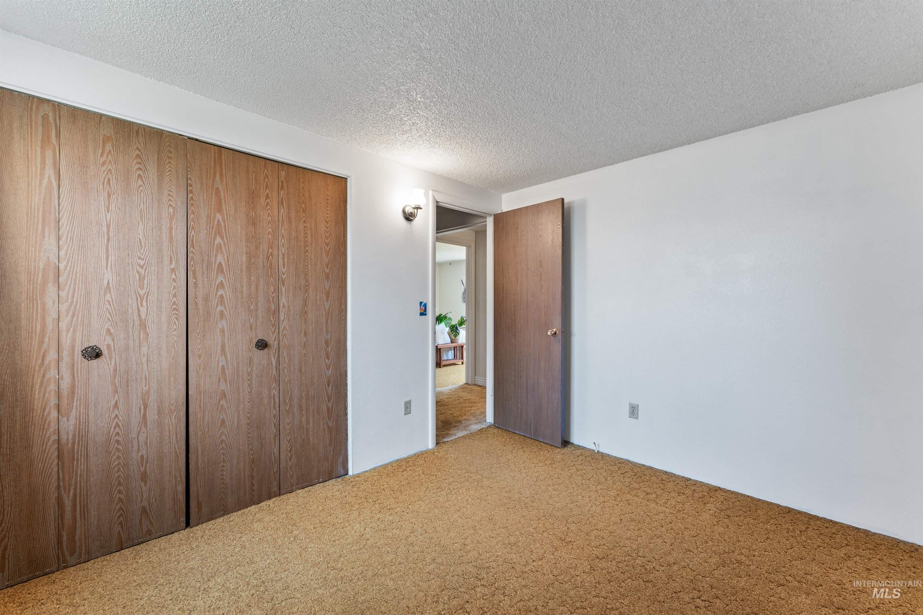 Unfurnished bedroom with carpet flooring, a closet, and a textured ceiling