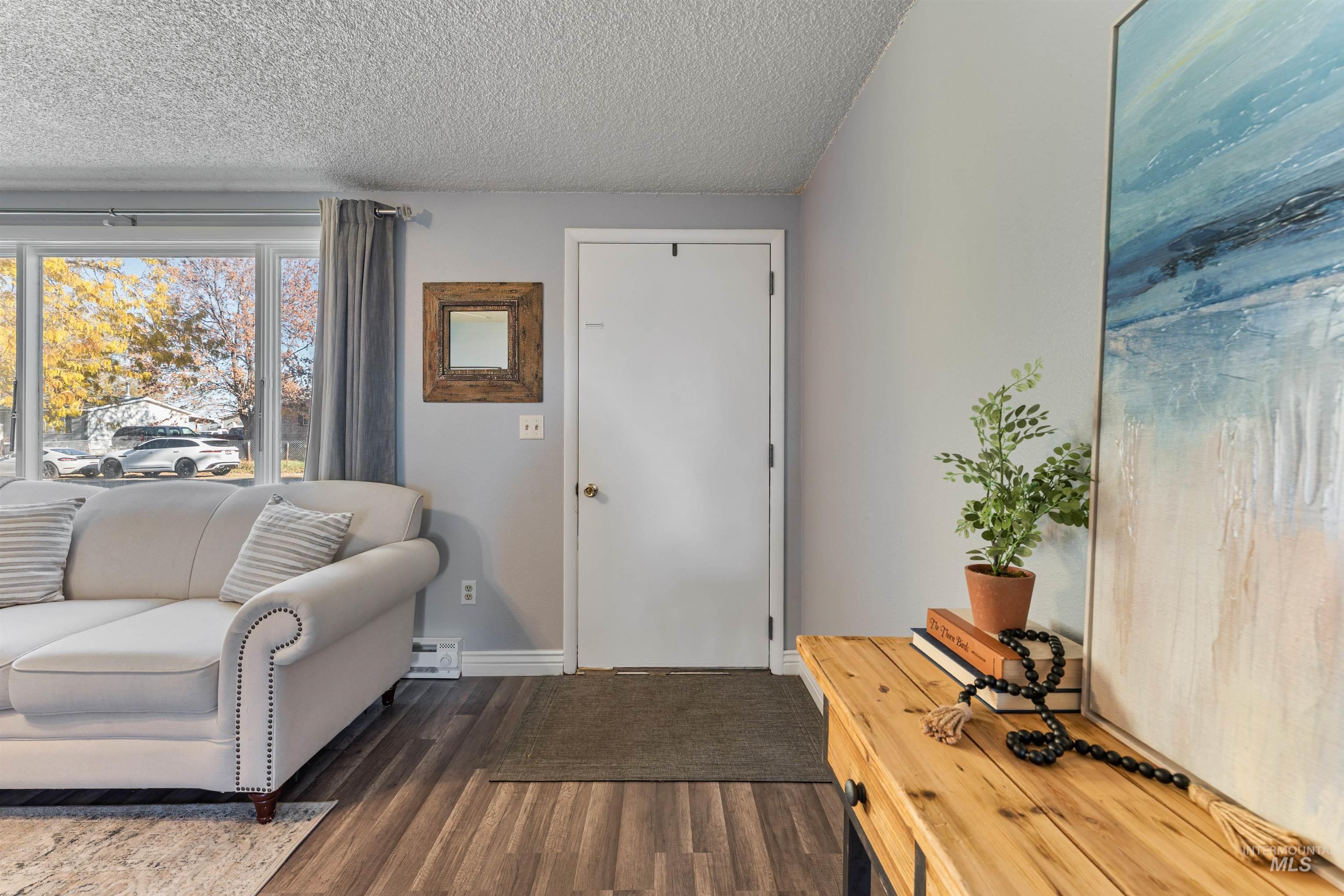 Living area with dark wood-style floors, a textured ceiling, and a baseboard radiator