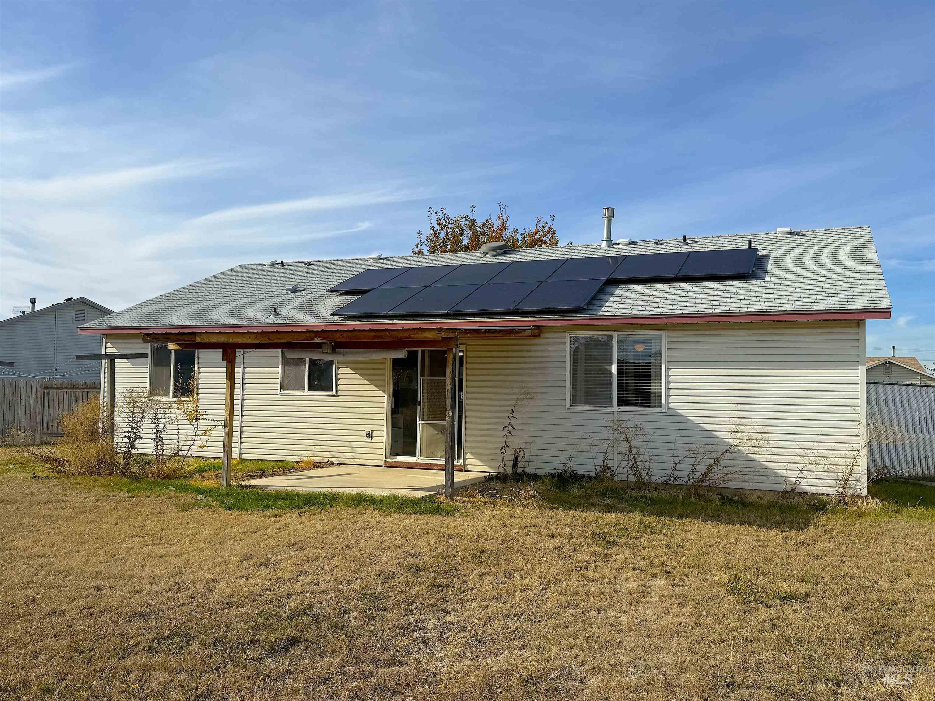 Rear view of house featuring a patio and roof mounted solar panels