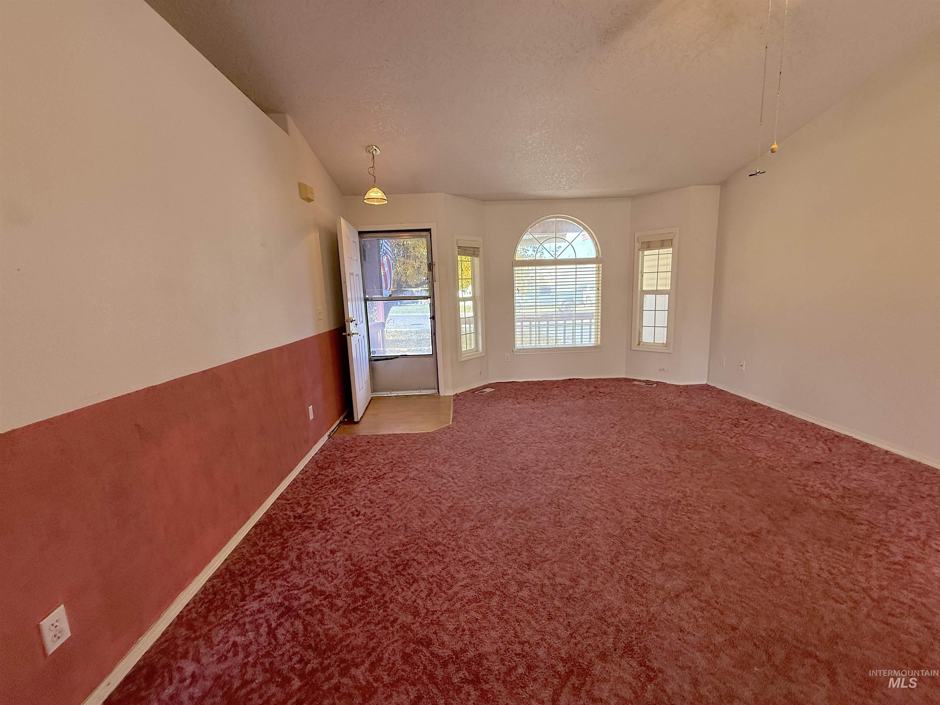 Carpeted empty room with baseboards and a textured ceiling