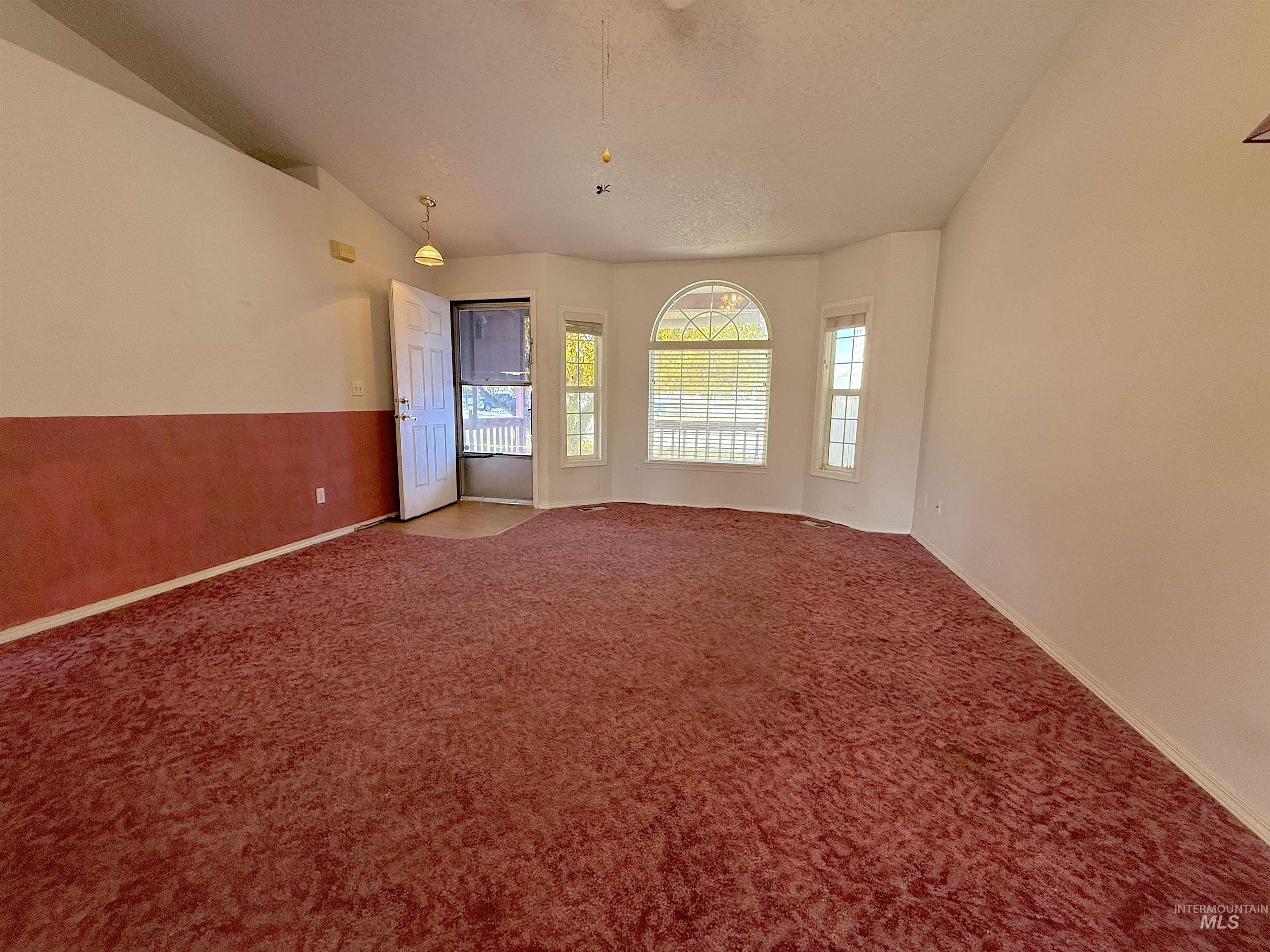 Carpeted spare room with lofted ceiling and a textured ceiling