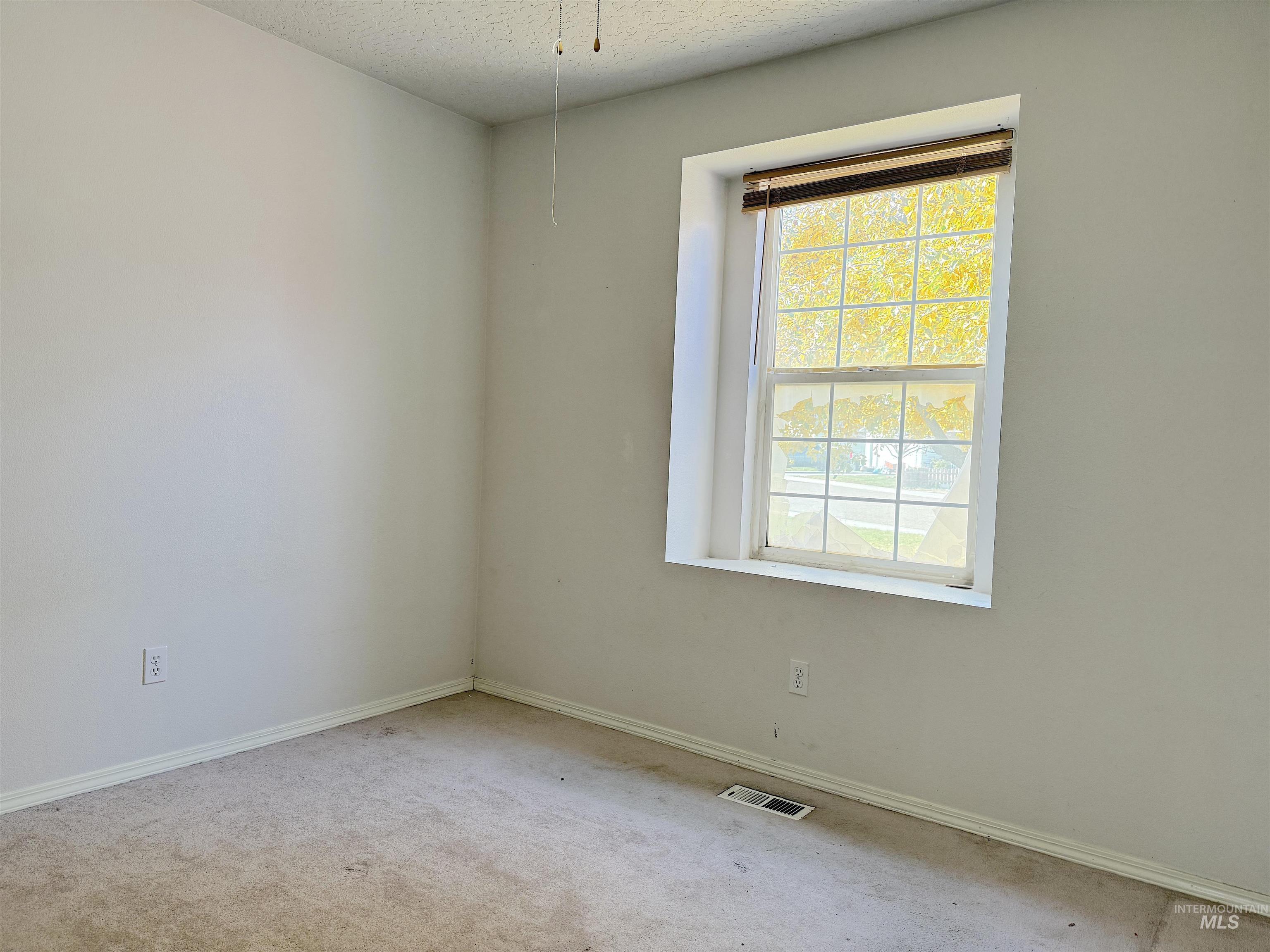 Carpeted spare room with a textured ceiling and baseboards