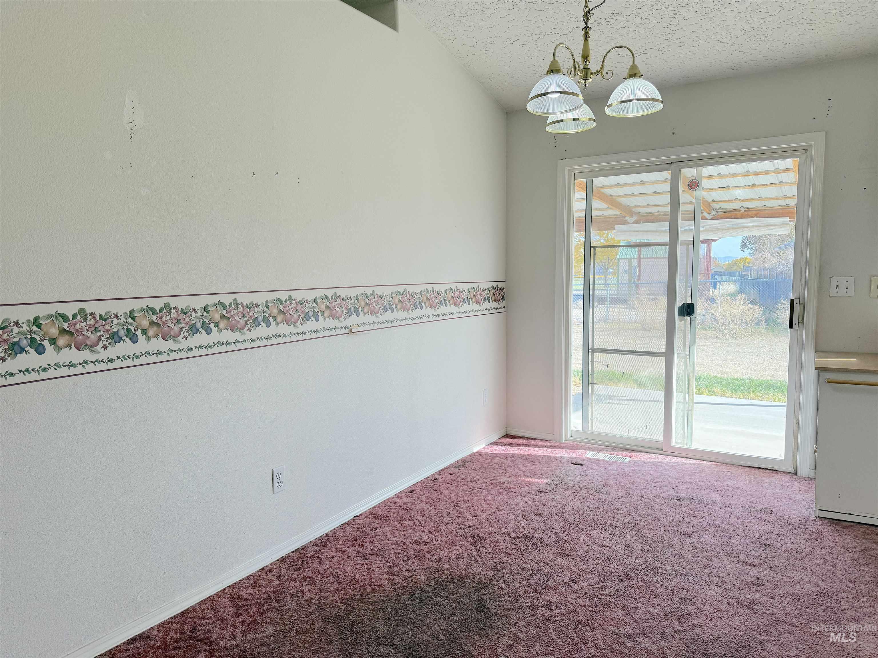 Unfurnished dining area with a textured ceiling, a chandelier, and carpet floors