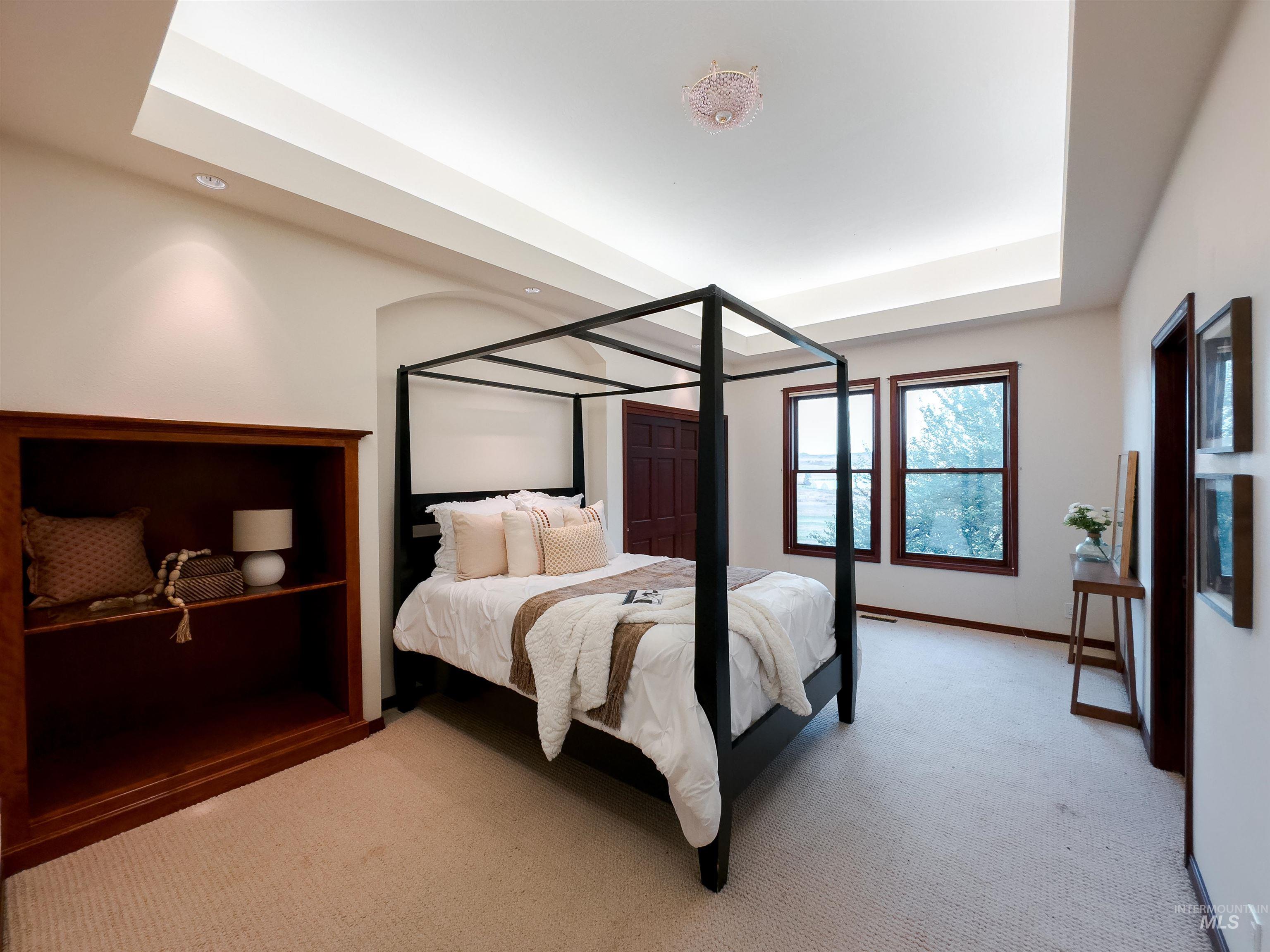 Bedroom featuring light colored carpet and a tray ceiling