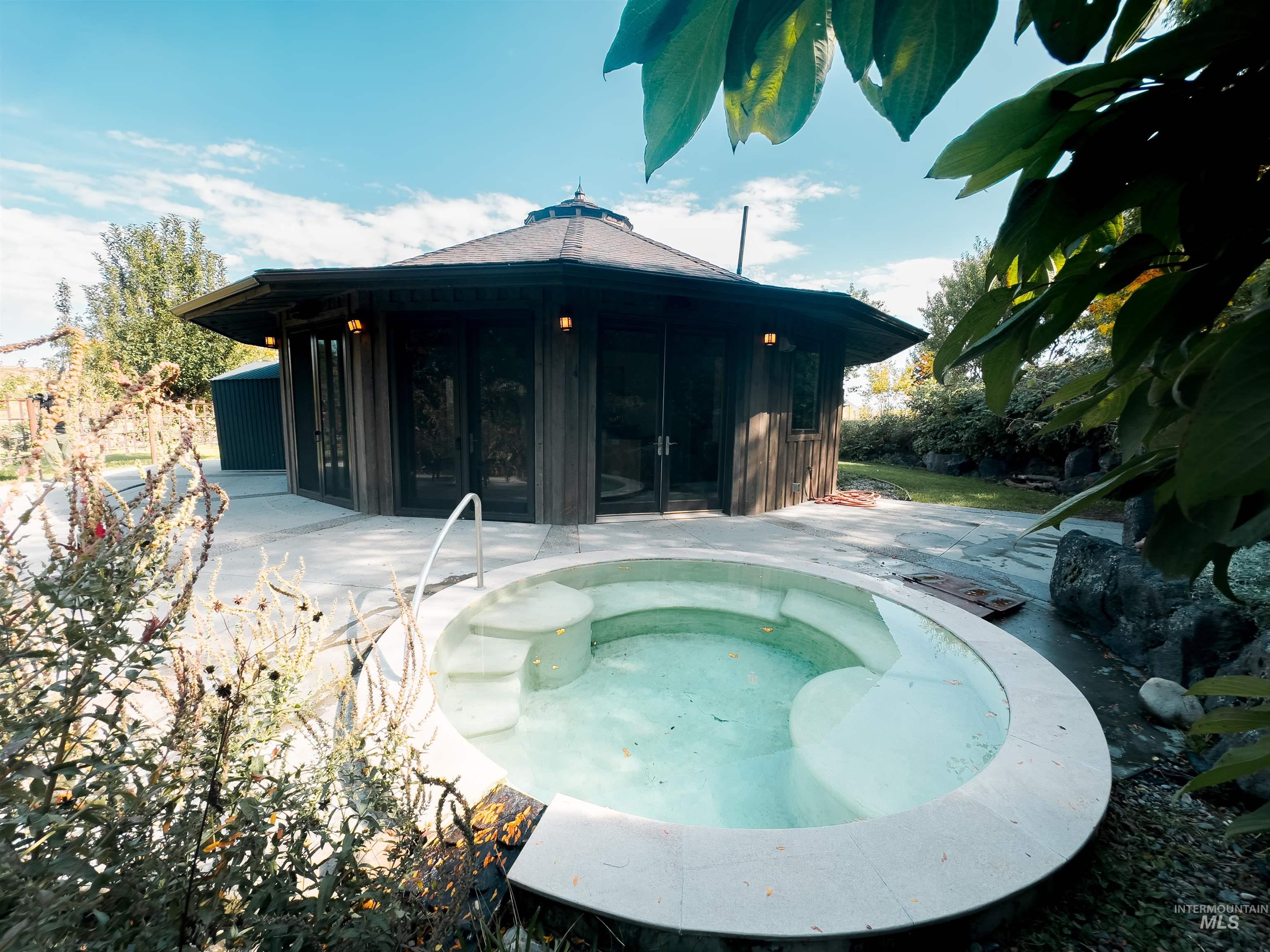 Rear view of house with an in-ground hot tub and a patio