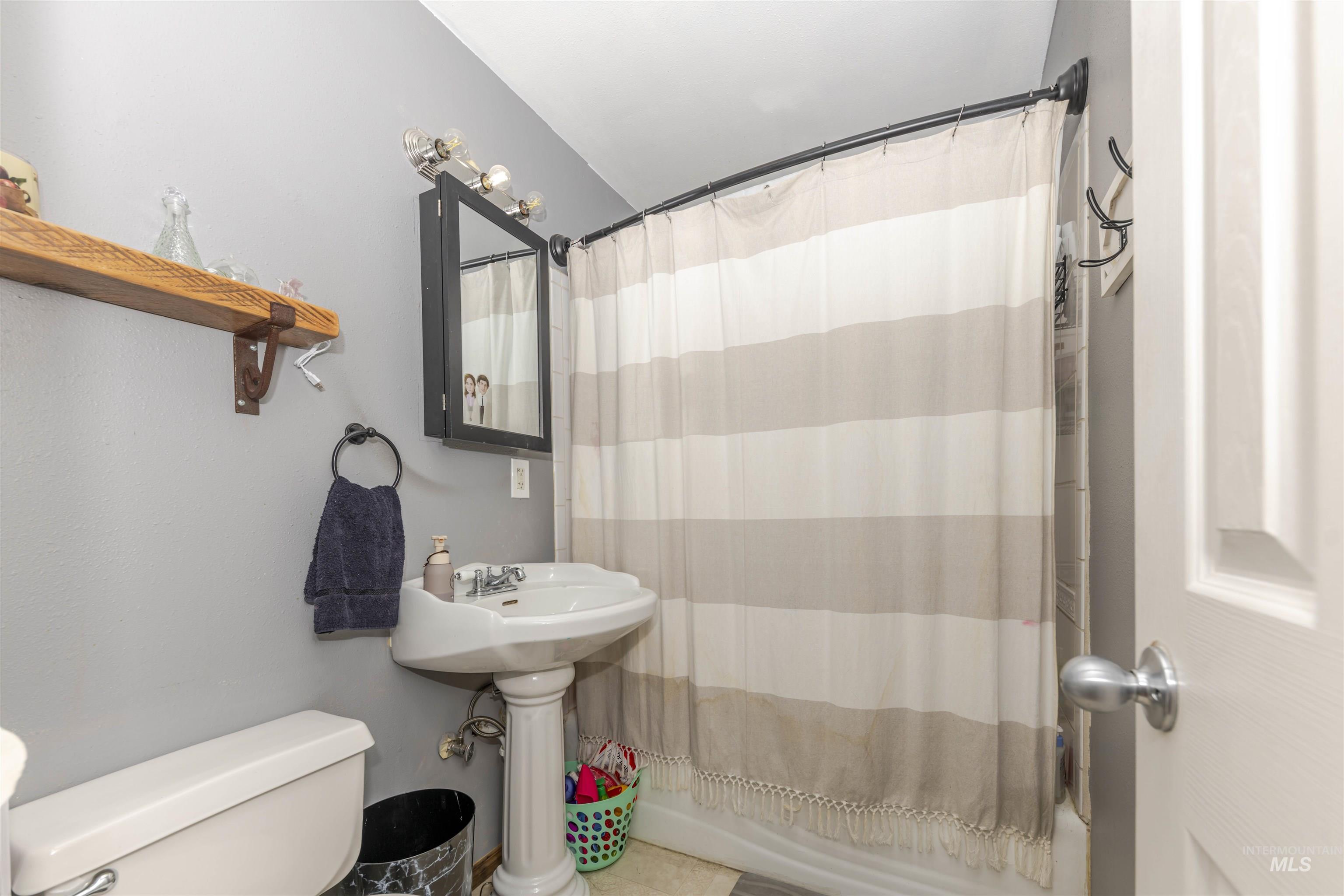 Bathroom with toilet and shower / bath combo with shower curtain