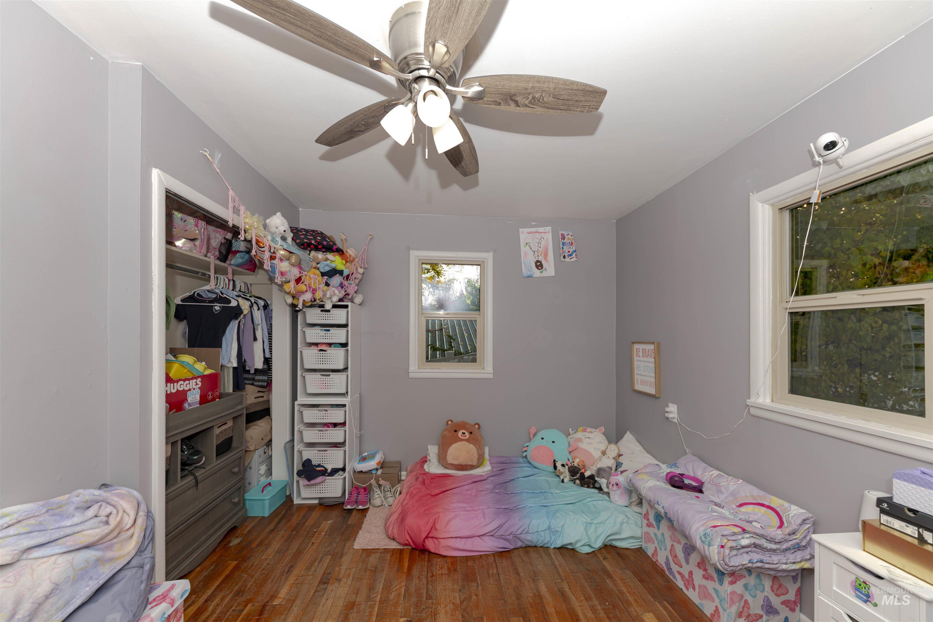 Bedroom with dark wood-type flooring, ceiling fan, and a closet