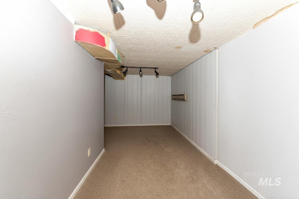 Finished basement with track lighting and light colored carpet