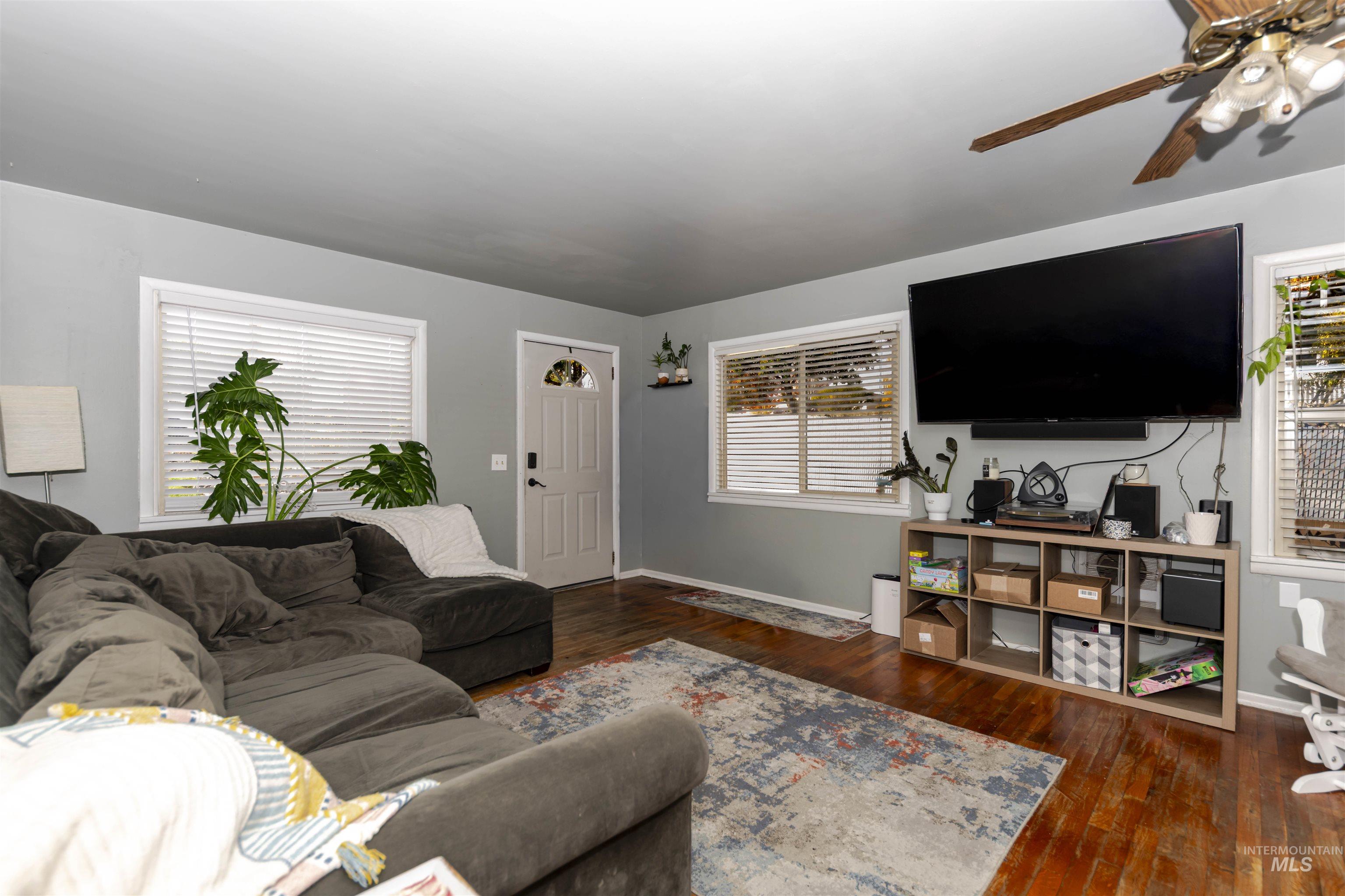 Living room featuring dark wood-style floors and ceiling fan