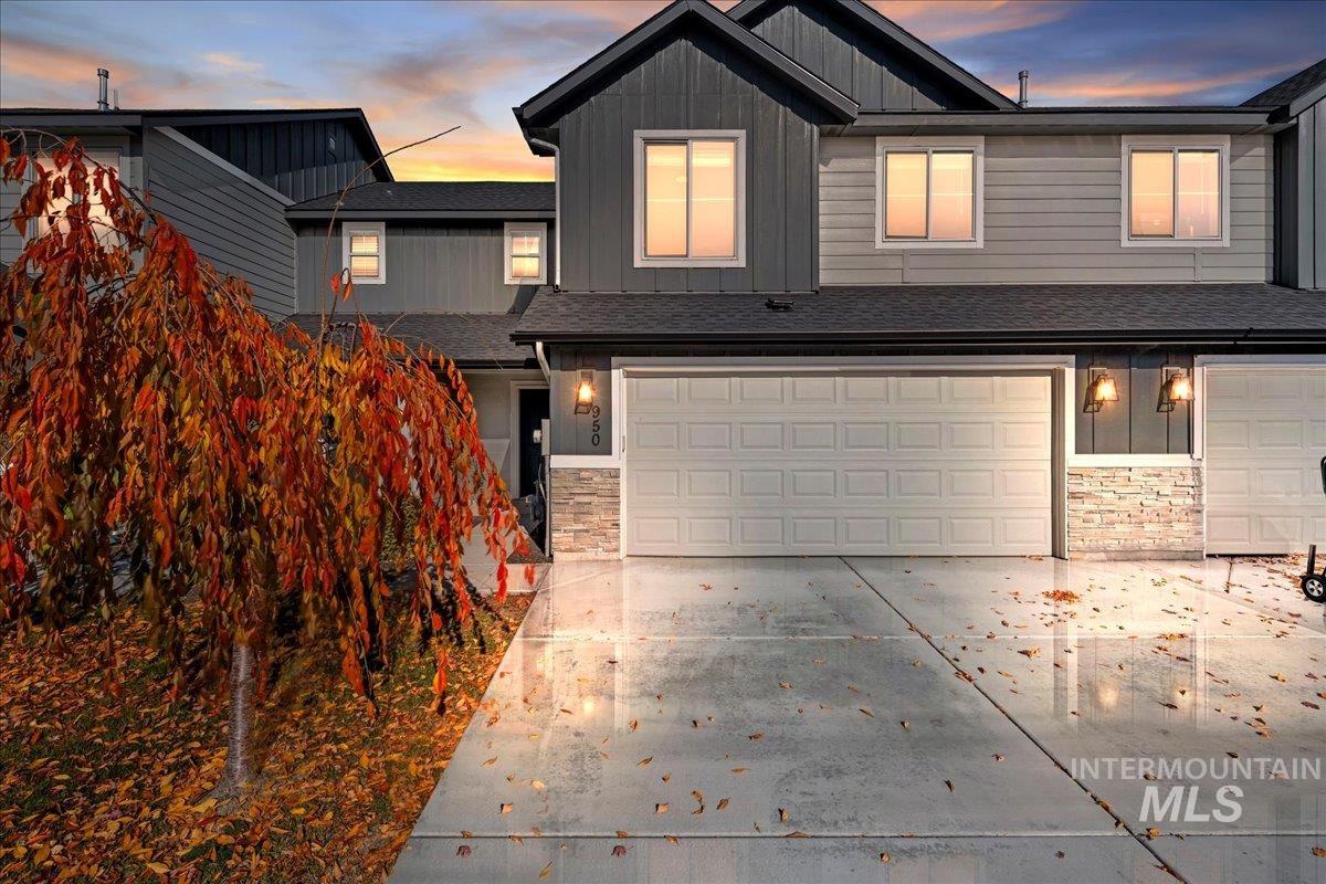 View of front facade featuring stone siding, board and batten siding, concrete driveway, and a garage