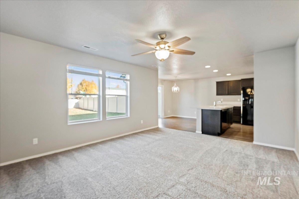 Unfurnished living room with light colored carpet, ceiling fan, a chandelier, and recessed lighting