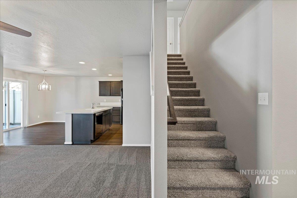 Stairway with carpet flooring, a textured ceiling, recessed lighting, and wood finished floors