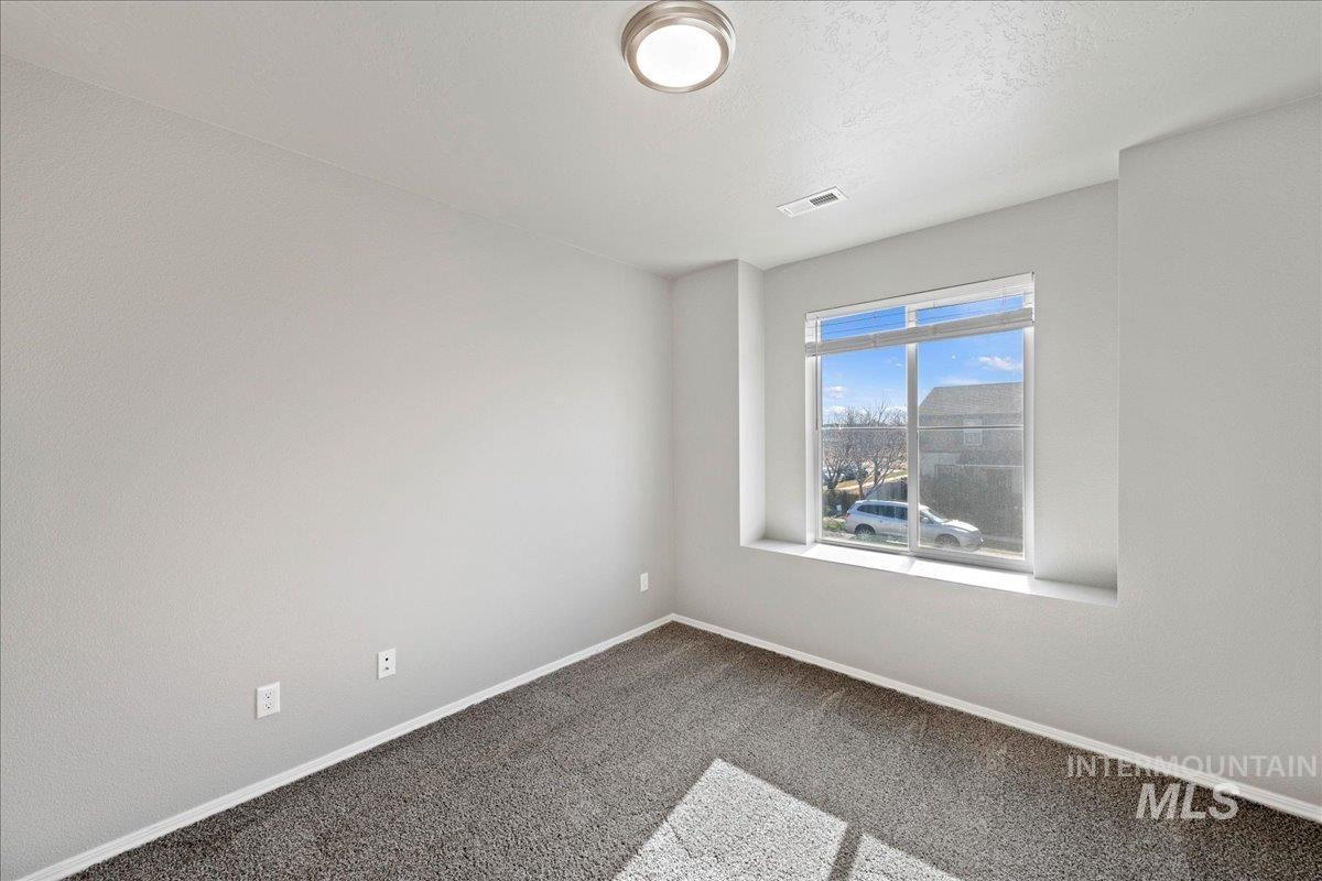 Carpeted spare room featuring baseboards and a textured ceiling