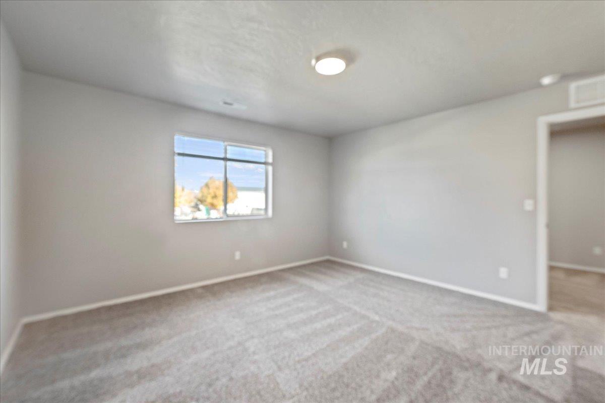 Spare room featuring light colored carpet and baseboards