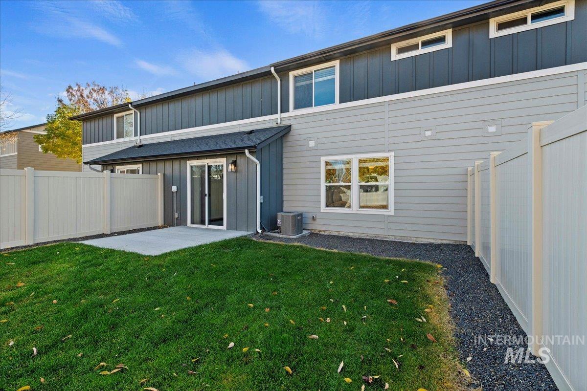 Rear view of house featuring a fenced backyard, a patio, and board and batten siding