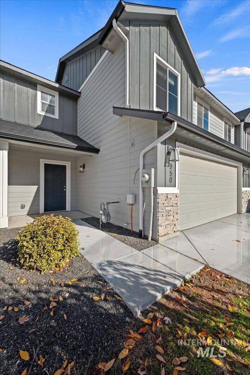 View of side of home featuring board and batten siding, a garage, and stone siding