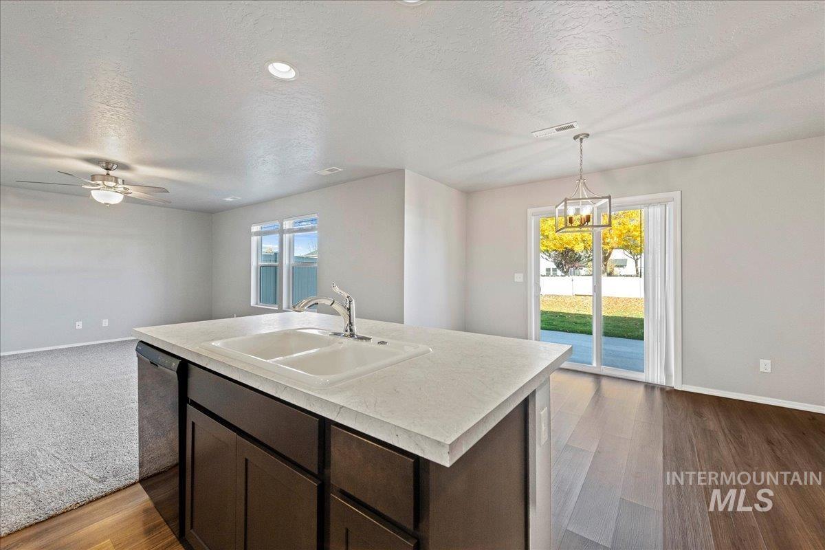 Kitchen featuring dark brown cabinets, light countertops, a textured ceiling, plenty of natural light, and pendant lighting