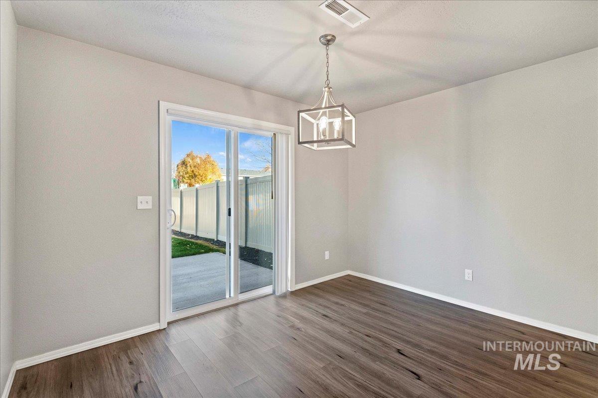 Unfurnished dining area with dark wood finished floors and a chandelier