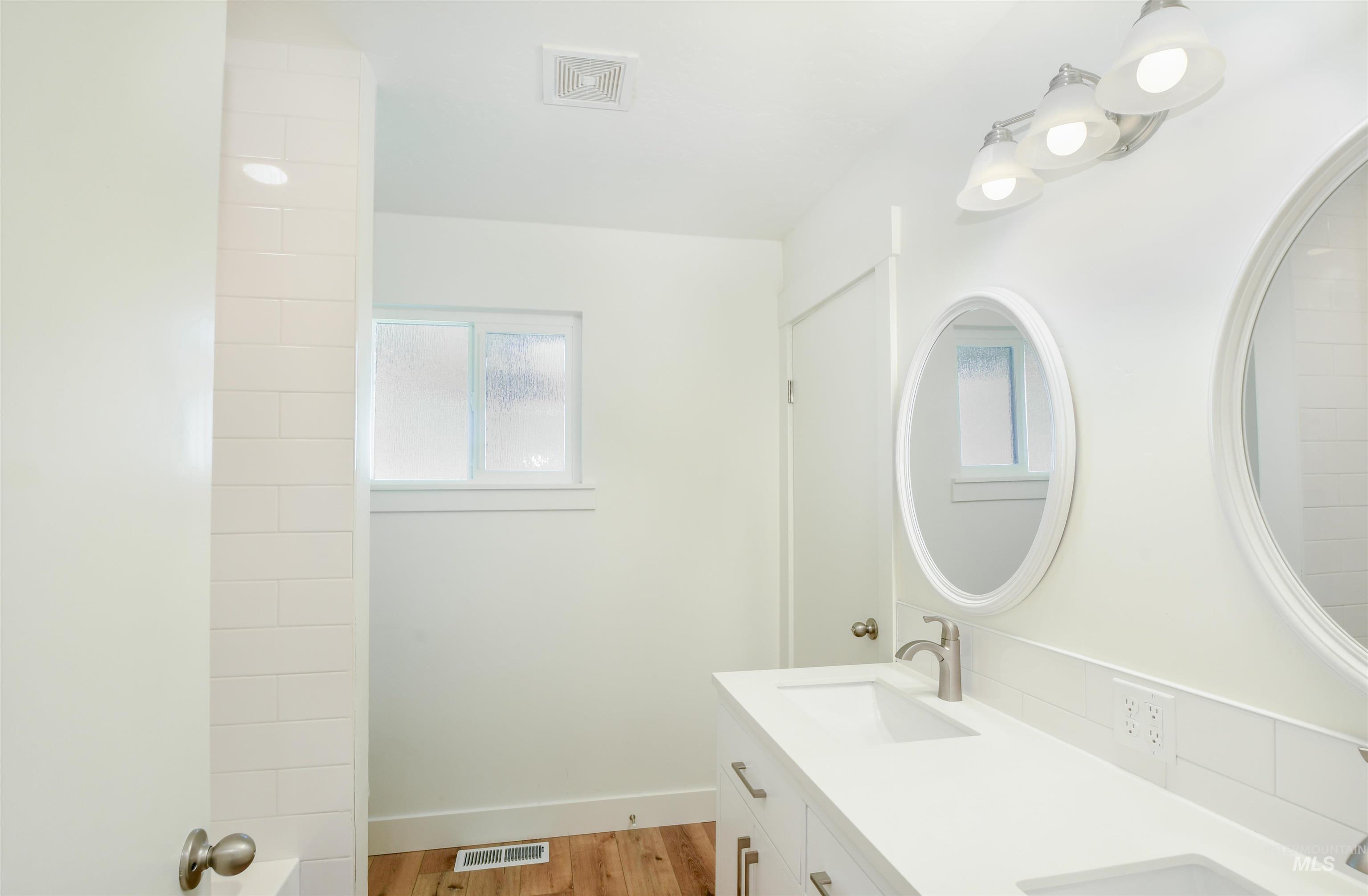 Bathroom with light wood finished floors and double vanity