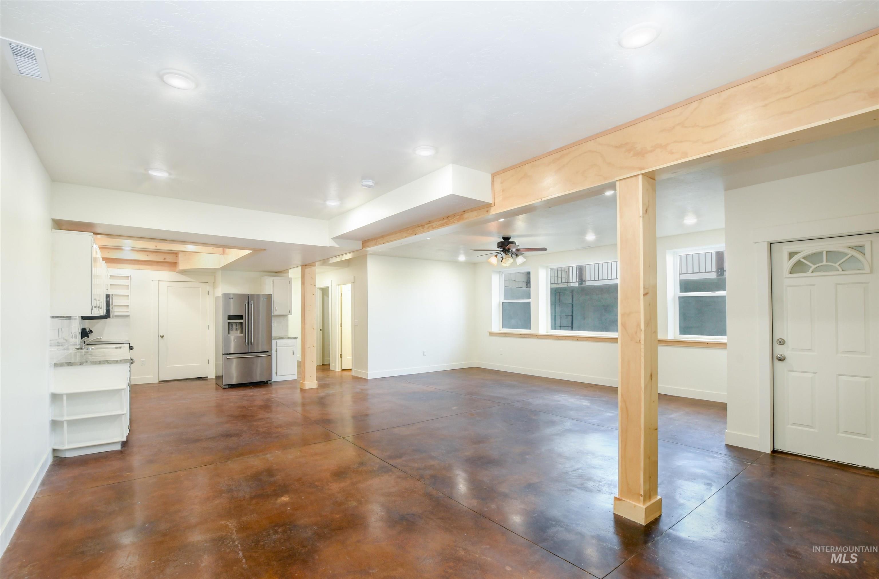 Unfurnished living room featuring concrete floors and ceiling fan