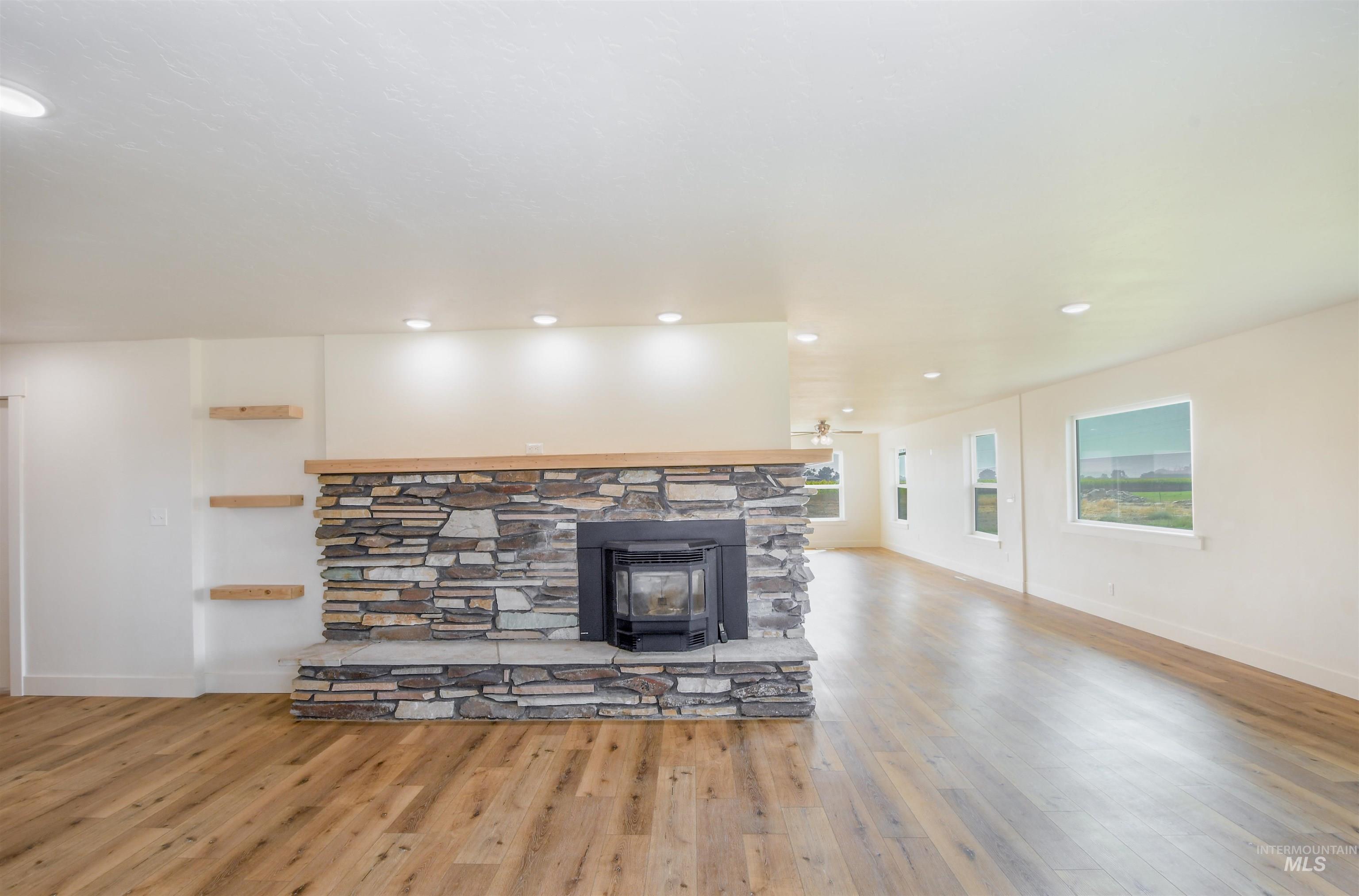 Unfurnished living room featuring light wood finished floors, recessed lighting, and a wood stove