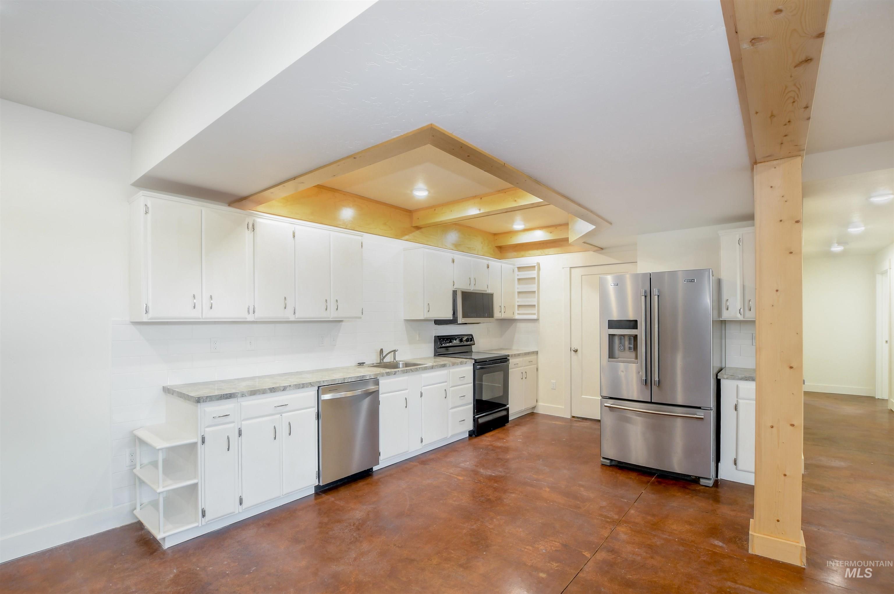 Kitchen with open shelves, stainless steel appliances, white cabinets, and finished concrete flooring