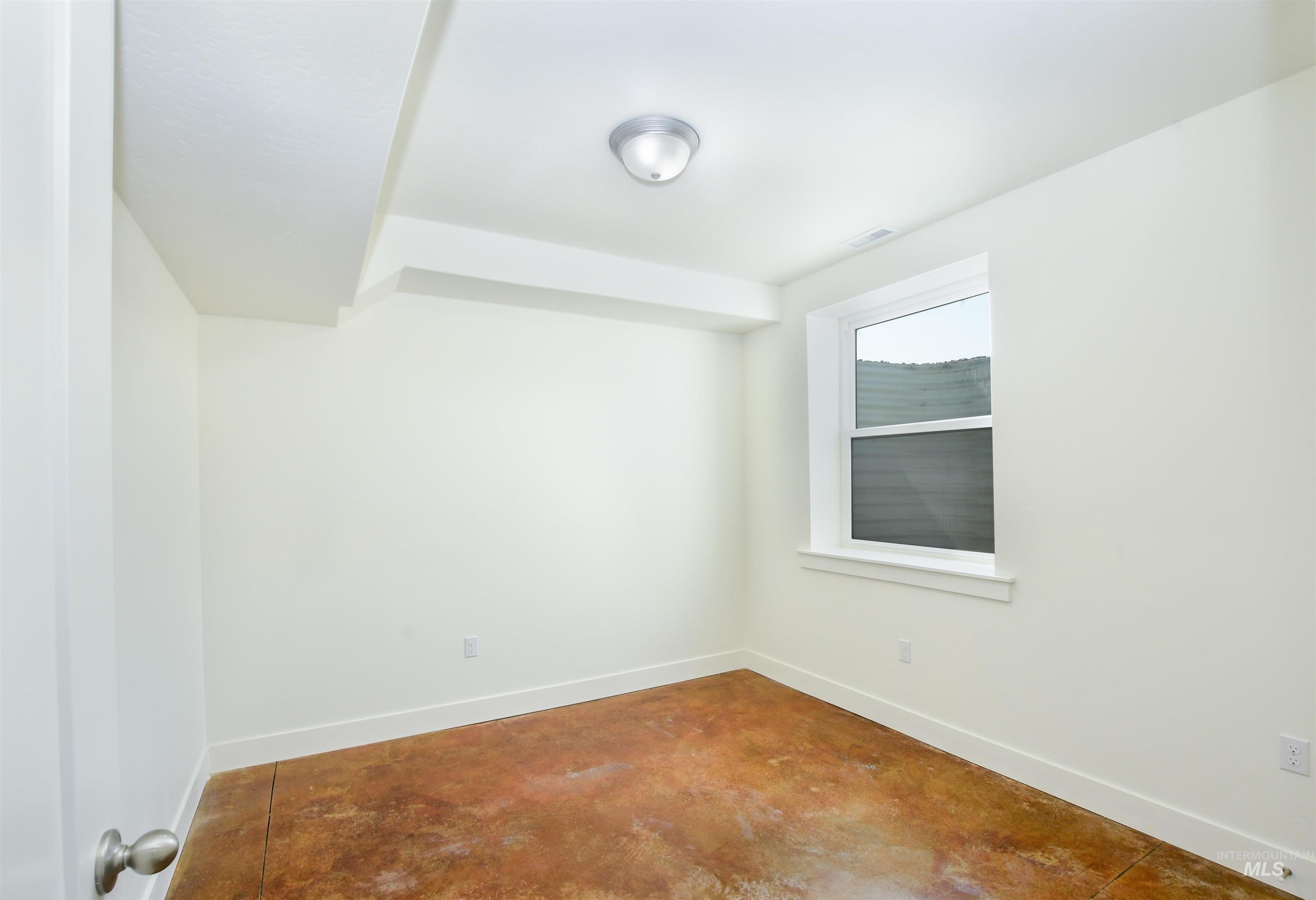 Empty room featuring baseboards and concrete flooring