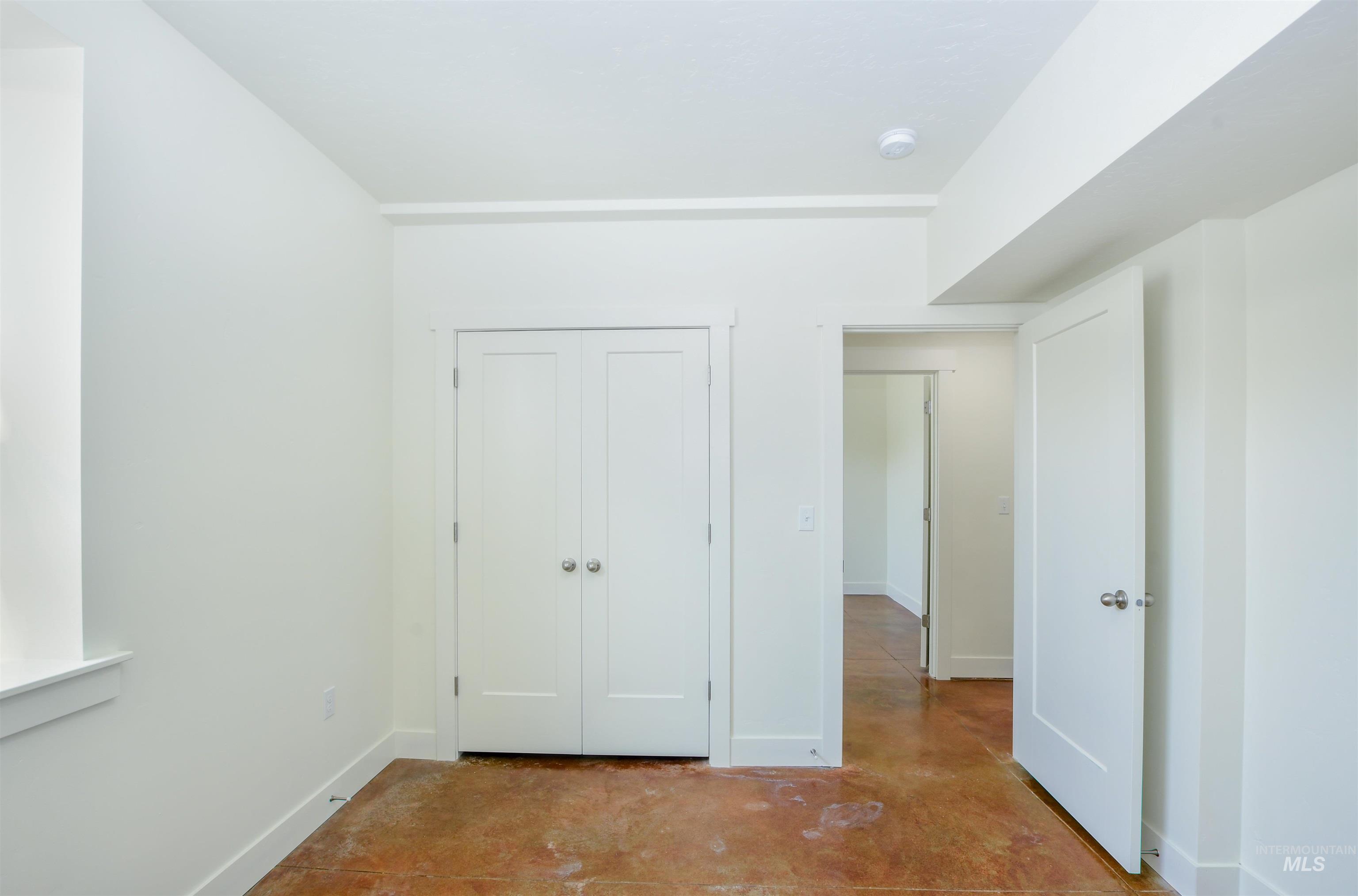 Unfurnished bedroom featuring concrete floors and a closet