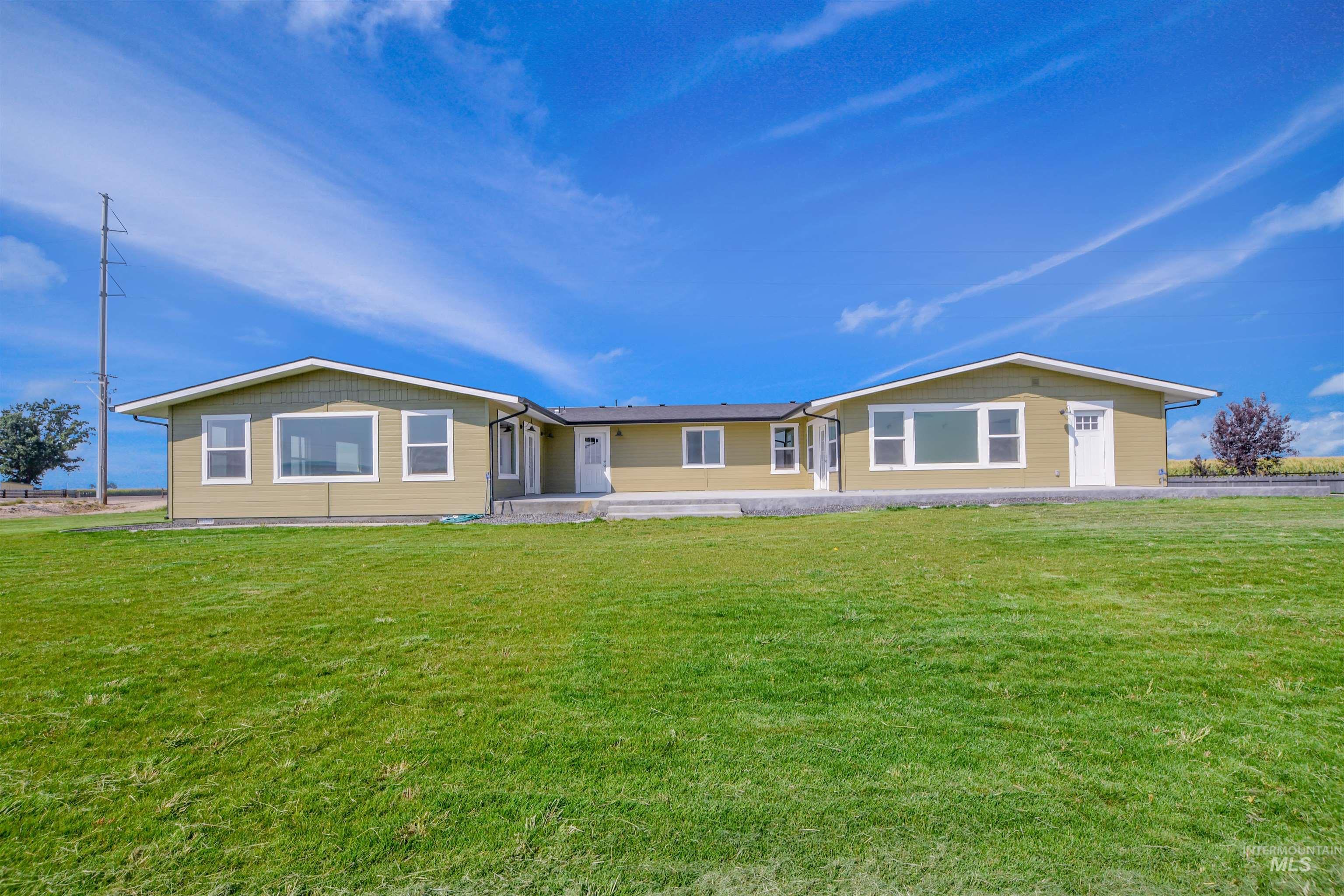 Rear view of property featuring a lawn, covered porch, driveway, and an attached garage