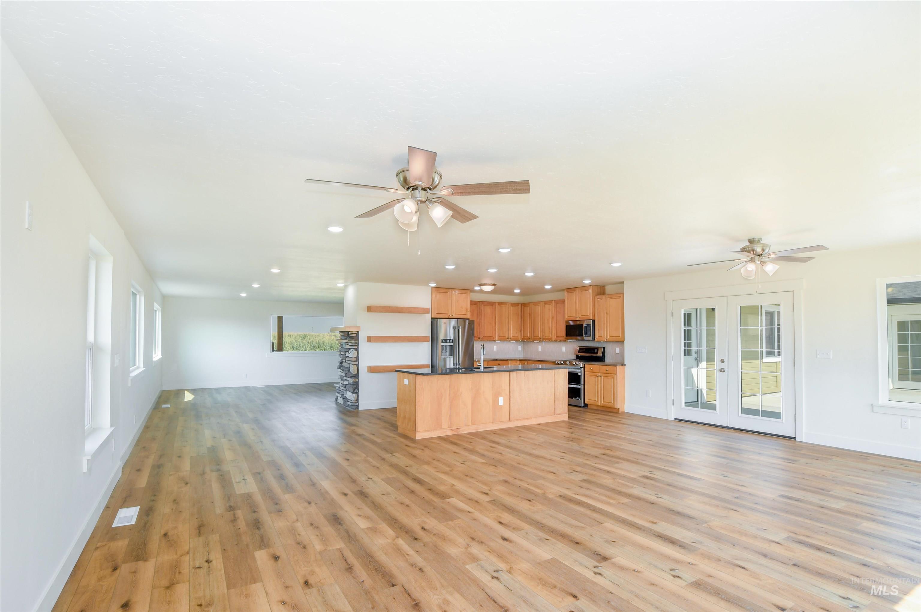 Unfurnished living room with a ceiling fan, recessed lighting, light wood finished floors, and french doors