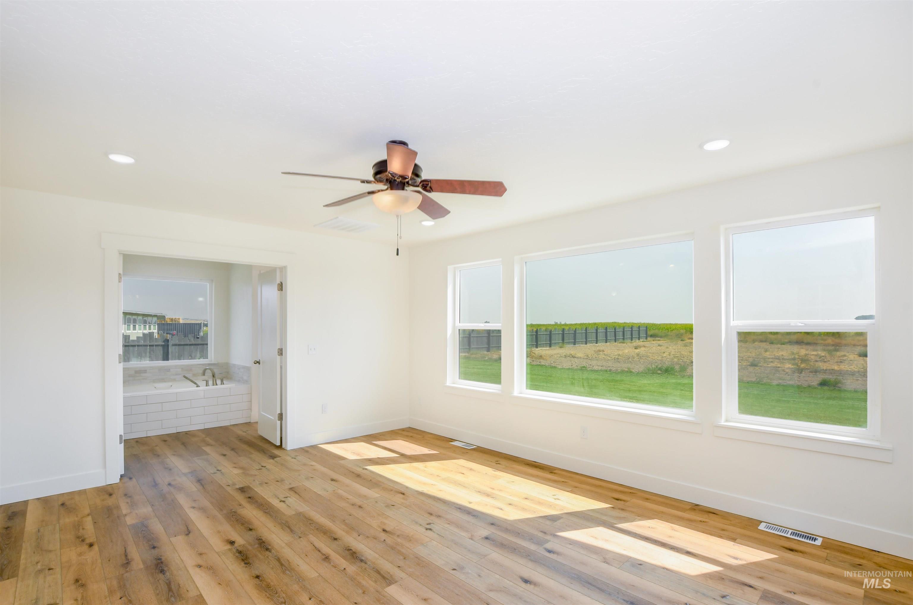 Empty room with plenty of natural light, light wood-style floors, a ceiling fan, and recessed lighting