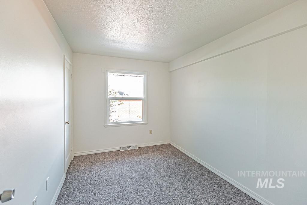 Carpeted spare room with a textured ceiling and baseboards