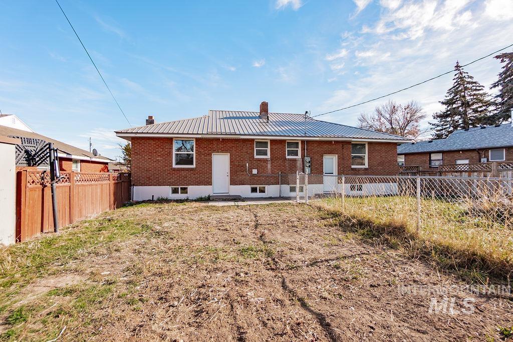 Back of house featuring a chimney, a metal roof, brick siding, and a patio area