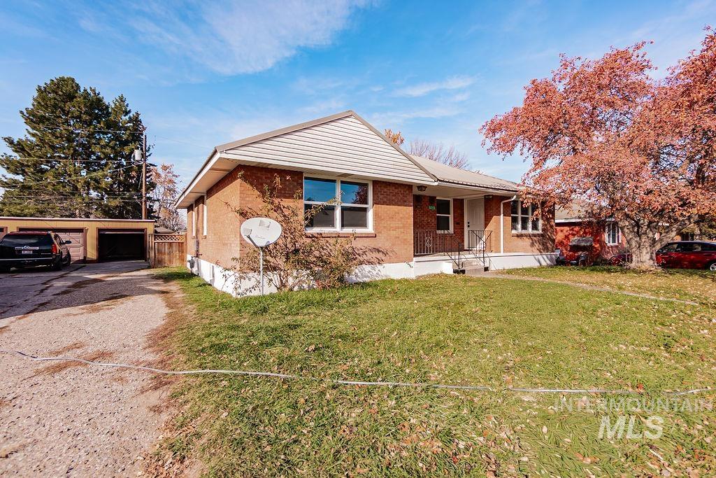 Ranch-style home featuring a front lawn, covered porch, an outbuilding, brick siding, and a garage