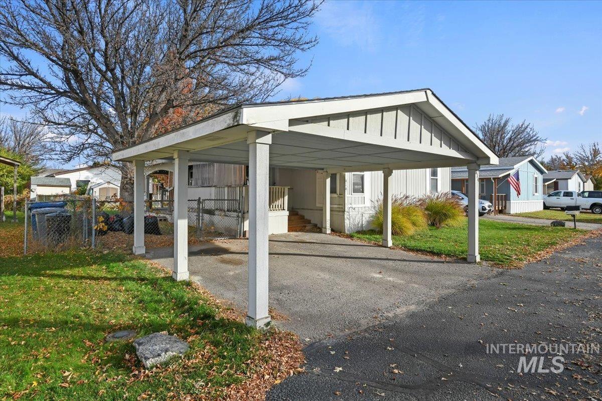 View of car parking with a gate, asphalt driveway, and a detached carport