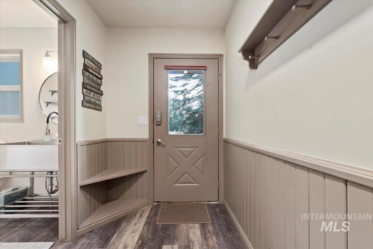 Doorway to outside with wood finished floors and a wainscoted wall