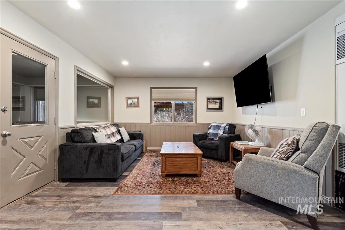 Living area with wood finished floors, recessed lighting, a wainscoted wall, and a heating unit