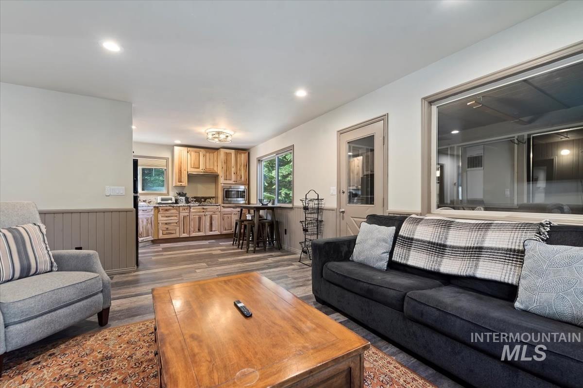 Living room with a wainscoted wall, dark wood-style flooring, and recessed lighting
