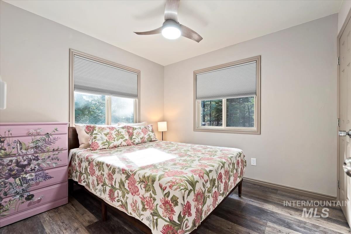 Bedroom with multiple windows, dark wood-style floors, and ceiling fan