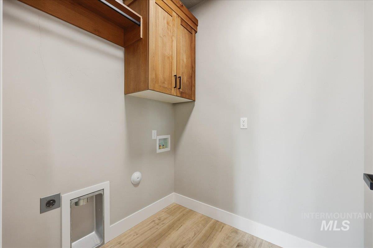 Laundry room with light wood-type flooring, hookup for a washing machine, electric dryer hookup, cabinet space, and hookup for a gas dryer
